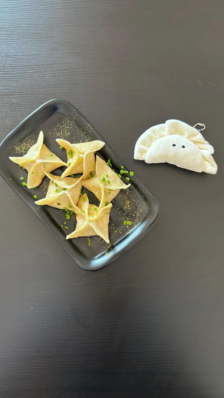 Gyozas plegadas en forma de estrella junto a un llavero de peluche con forma de gyoza