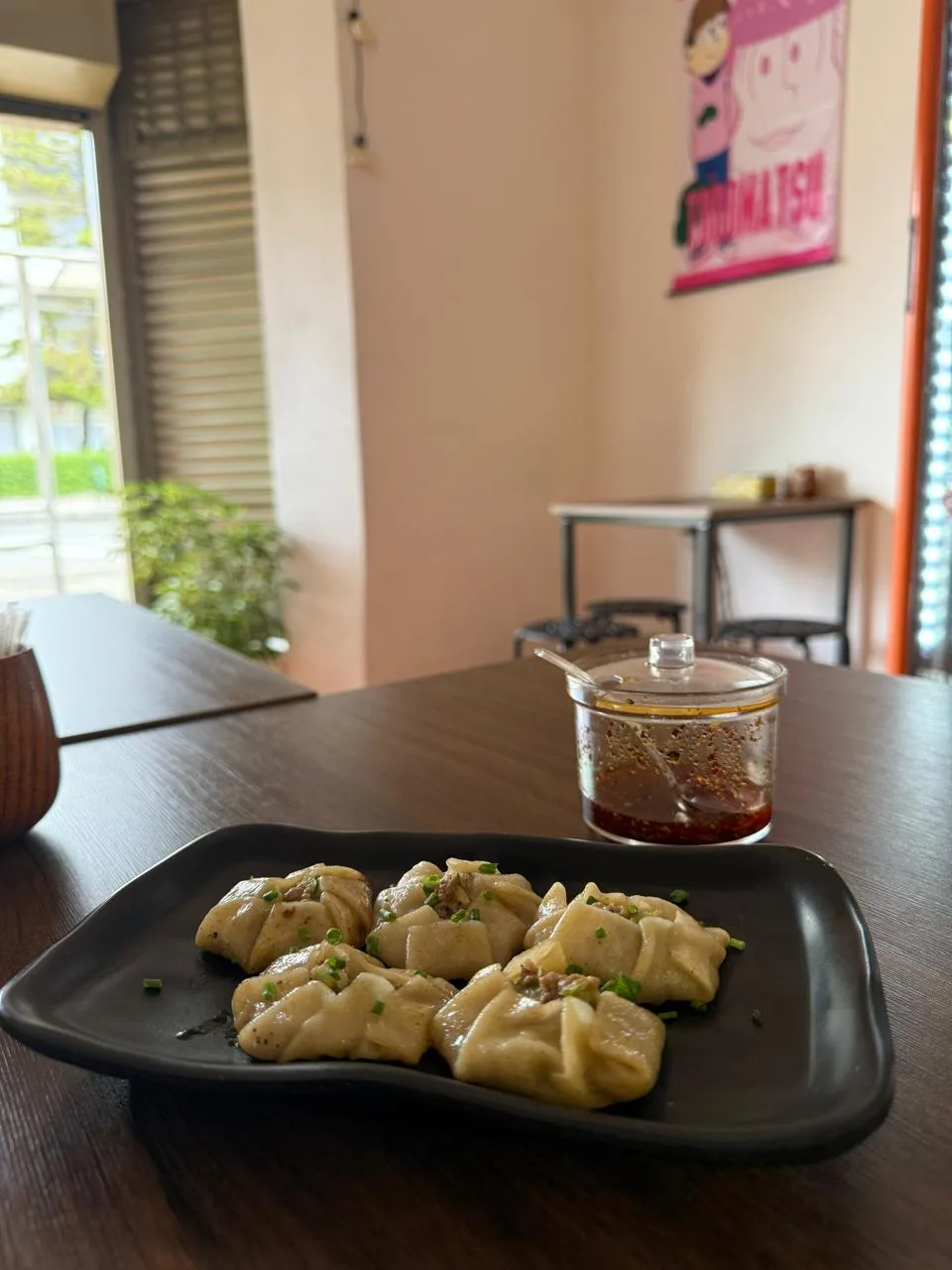 Plato de gyozas y un frasco de salsa en una mesa del salón, junto a la ventana
